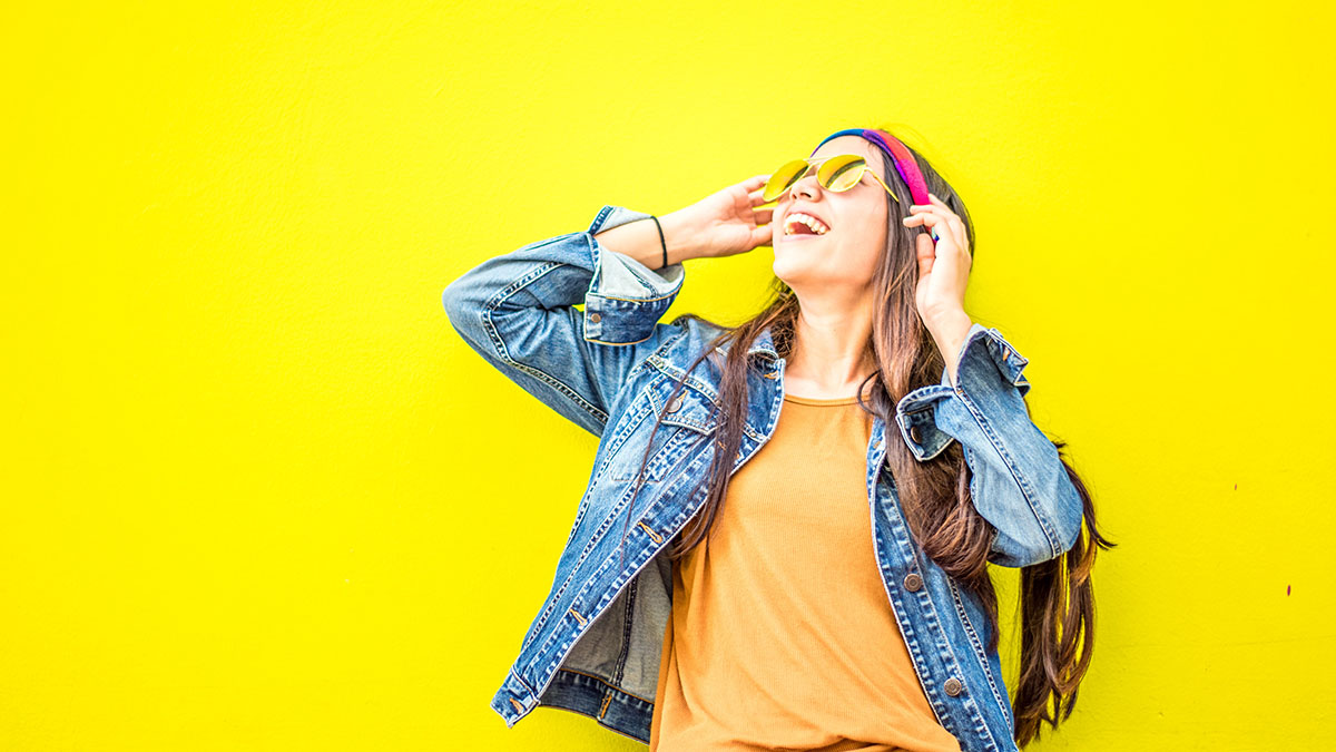 Trendy smiling woman on a yellow background